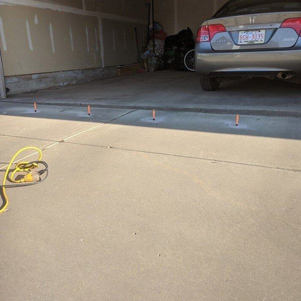 A garage leveling marker on the driveway surface by Sunny South Insulators in Calgary, AB