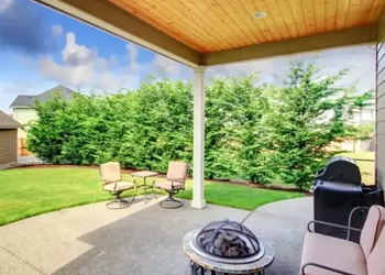 Covered backyard patio with level concrete surface and seating in Calgary, AB